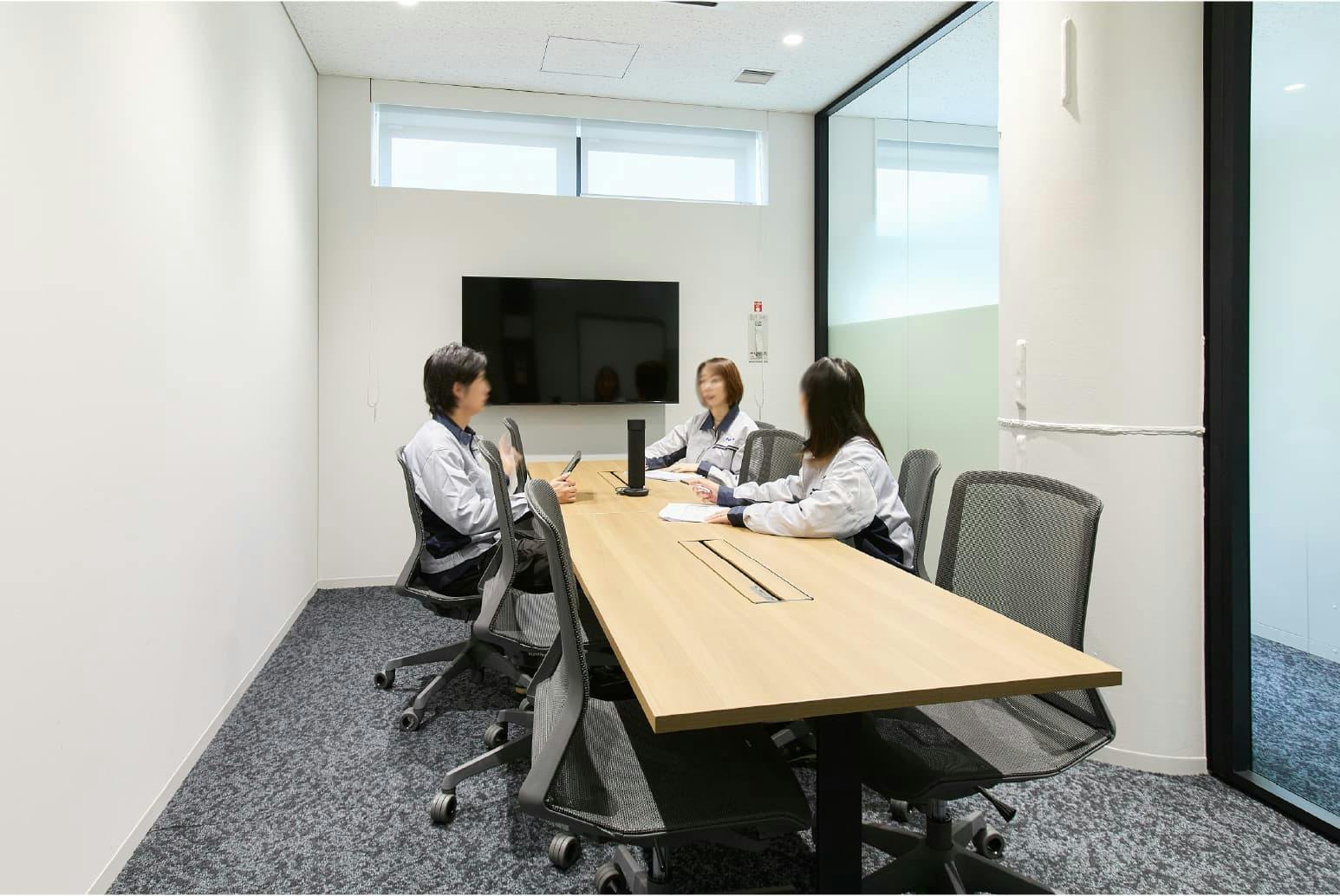 日東電工株式会社 様の事例写真／[5F 会議室]モニター完備の会議室。移動が簡単なキャスター付きのイスが、各室色違いで配置してあります。外から陽光が差し込む明るい会議室では、活発な意見が交わされています。